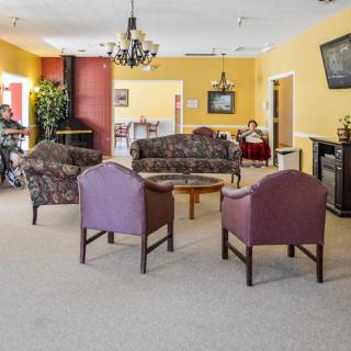 A cozy living area with sofas, chairs, a table, and a television.