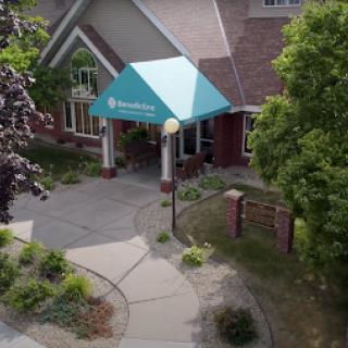 A welcoming entrance with a blue canopy surrounded by lush greenery.
