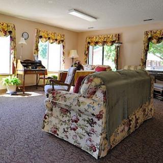 A cozy living room filled with natural light, featuring floral-patterned furniture and elegant window treatments.
