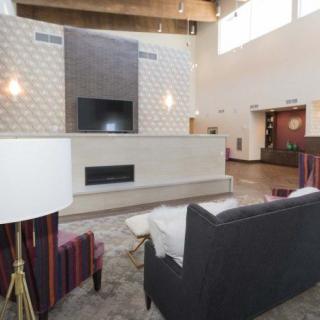 A modern living room with contemporary furniture, a wall-mounted television, and a built-in fireplace.