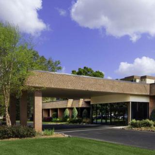 A hotel entrance with landscaped surroundings and a clear blue sky.