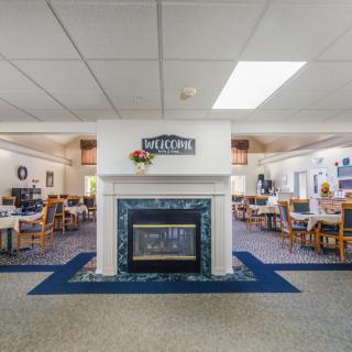 A cozy dining area with a central fireplace dividing the space, featuring tables and chairs arranged neatly around the room.