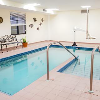 An indoor swimming pool equipped with a bench and a lift for accessibility.