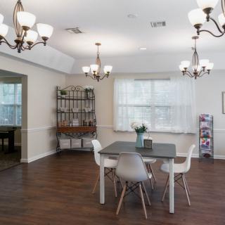 A modern dining area with elegant chandeliers, minimalist furniture, and a wooden floor.