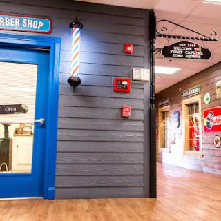 A vibrant interior of a barber shop featuring a blue door and traditional striped barber pole.