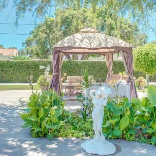 A beautifully landscaped garden featuring a gazebo and a stone statue surrounded by lush greenery.