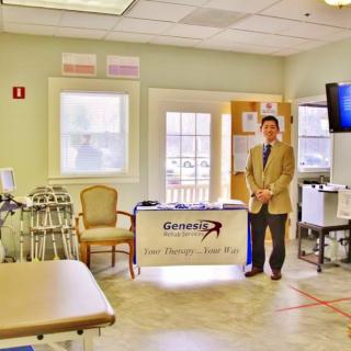 A professional standing in a medical clinic with various equipment and a welcoming setup.