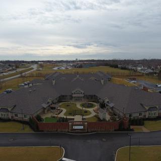 An aerial view of a residential complex featuring green spaces and pathways under a cloudy sky.