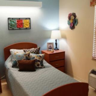 A cozy bedroom with a single bed, decorated with pillows and artwork on the walls.