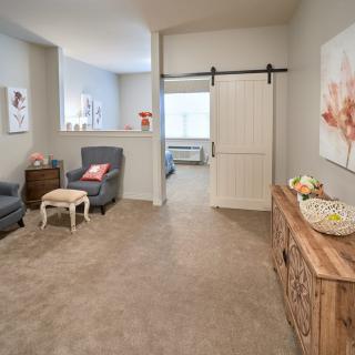 A cozy, elegantly designed living room featuring comfortable armchairs, a rustic wooden console table, and a sliding barn door leading to another space.