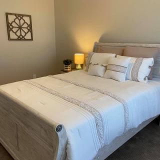 A cozy and well-decorated bedroom with a neatly made bed, bedside lamp, and wall art.