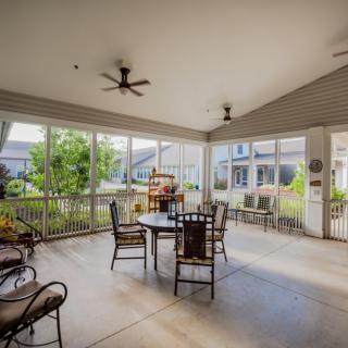 A cozy screened patio with comfortable seating and ceiling fans, perfect for outdoor relaxation.