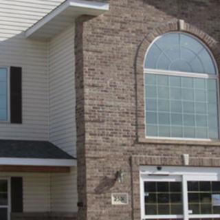 A residential building with a brick facade and large arched window.