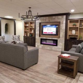 A modern living room with comfortable sofas, a television above a fireplace, and built-in bookshelves.