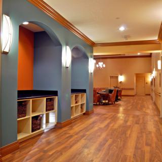A modern hallway featuring wood flooring, colorful walls, recessed shelving units, and contemporary lighting fixtures.