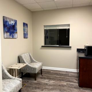 A modern office waiting area featuring comfortable seating and decorative artwork.