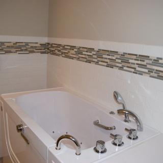 A modern bathroom with a built-in bathtub and decorative tile accents.
