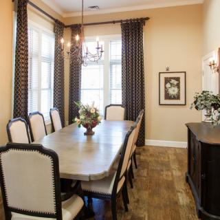 A beautifully decorated dining room with a large table, elegant chairs, and ambient lighting.