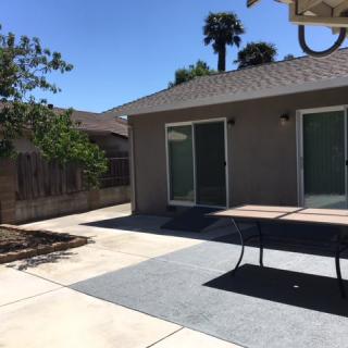 A sunny backyard patio with outdoor furniture and sliding glass doors.