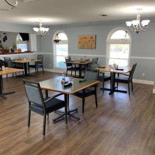 A cozy dining area with neatly arranged tables and chairs, featuring elegant lighting and decor.