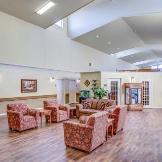 A spacious lobby area featuring comfortable seating arrangements and wooden flooring.