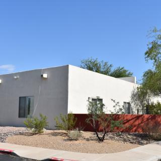 A modern white building set against a clear blue sky with desert landscaping.