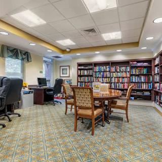 A cozy library room with bookshelves, a round table, and computers for study.