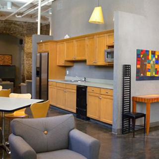 A modern kitchen and living area with wooden cabinets and colorful artwork.