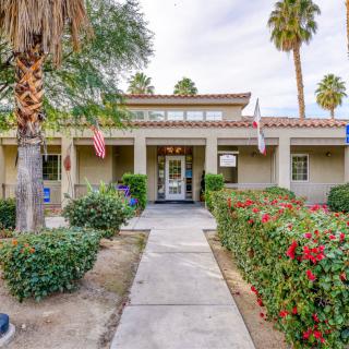 A building entrance surrounded by palm trees and well-maintained landscaping.