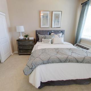 A cozy bedroom with a neatly made bed, nightstand, and decorative elements.