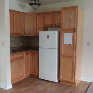 A compact kitchen with wooden cabinets and a refrigerator.