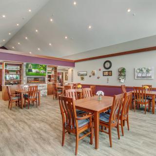 A cozy restaurant dining area with neatly arranged tables and chairs, featuring warm decor and hardwood flooring.
