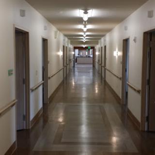 A long, well-lit hallway with doors on either side.