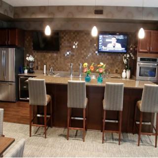 A modern kitchen with a sleek counter, bar stools, and stainless steel appliances.