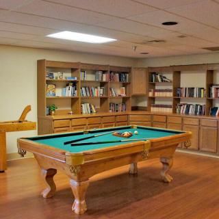 A recreation room featuring a billiard table and bookshelves filled with books.