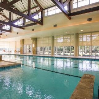 A spacious indoor swimming pool surrounded by large windows allowing natural light to fill the area.