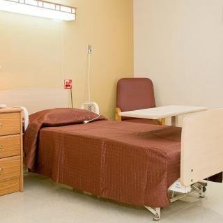 A clean and organized hospital room with a single bed and medical equipment.