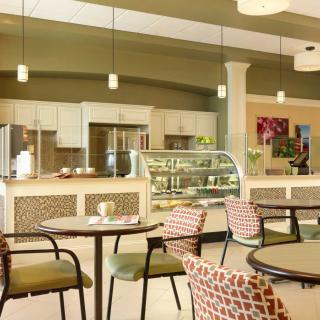 A modern cafe interior with tables and chairs, featuring a glass display counter.