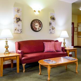 A cozy living room with a red sofa, wooden coffee table, and decorative lamps.