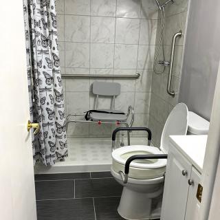An accessible bathroom with a shower chair and grab bars for safety.