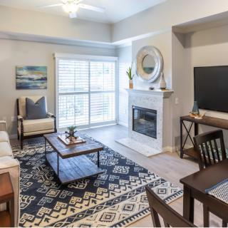 A modern living room with a cozy fireplace and stylish decor, featuring a patterned rug and natural light.