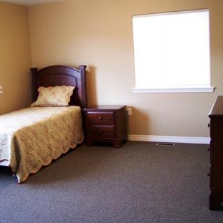 A minimalist bedroom with a single bed, nightstand, and dresser.