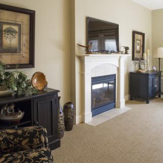 A cozy living room featuring a central fireplace, elegant furniture, and tasteful decor.