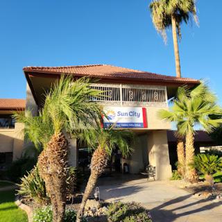 A picturesque resort entrance surrounded by lush palm trees on a bright sunny day.