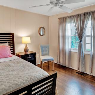 A cozy bedroom with a bed, lamp, and chair near the window covered with curtains.