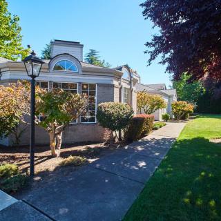 A charming residential house surrounded by well-maintained landscaping on a sunny day.