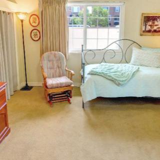 A cozy bedroom with a bed, rocking chair, and window.