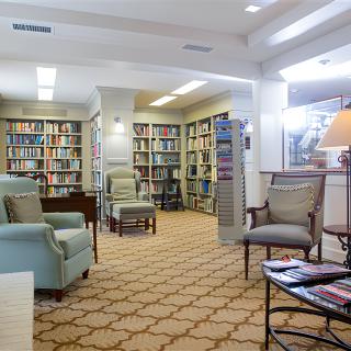 A cozy library reading area with comfortable armchairs and bookshelves filled with a variety of books.