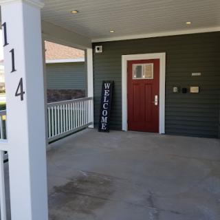 A welcoming front porch with a red door and a welcome sign.