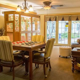 A cozy dining room with wooden furniture and ample natural light streaming through large windows.